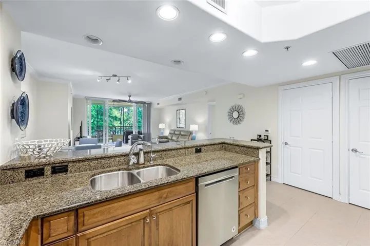 Kitchen with sink, light tile patterned floors, dishwasher, and light stone countertops
