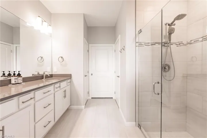 Primary bathroom with tile shower, frameless glass doors and walk in closet