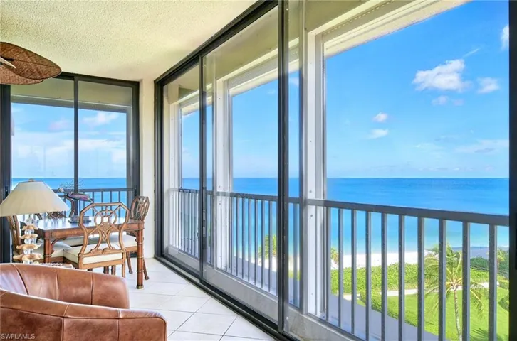 Sunroom with a textured ceiling, a water view, a wall of windows, and tile patterned floors