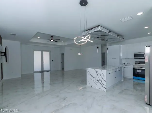 Kitchen with appliances with stainless steel finishes, modern cabinets, white cabinets, a raised ceiling, and a center island