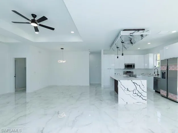 Kitchen with appliances with stainless steel finishes, modern cabinets, white cabinetry, light countertops, and a ceiling fan