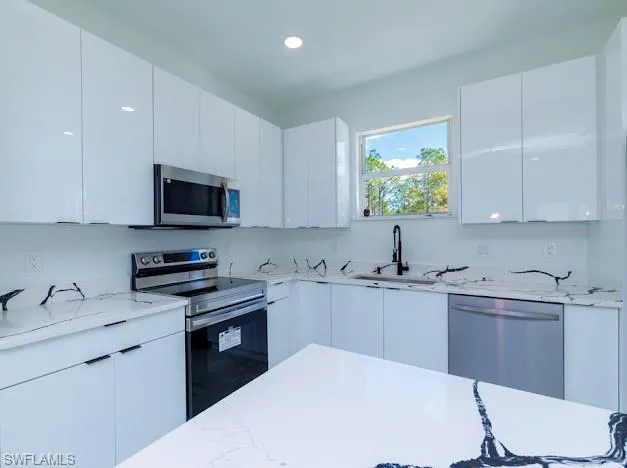 Kitchen featuring appliances with stainless steel finishes, white cabinetry, modern cabinets, and recessed lighting