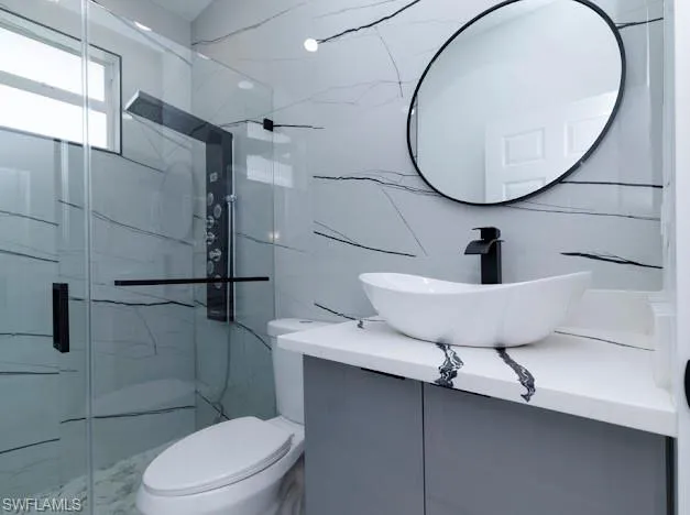 Full bath with vanity and a marble finish shower