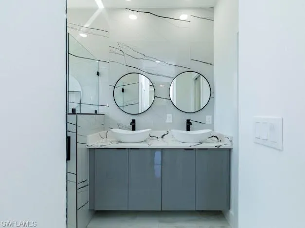Full bathroom with double vanity, marble finish floors, and a marble finish shower