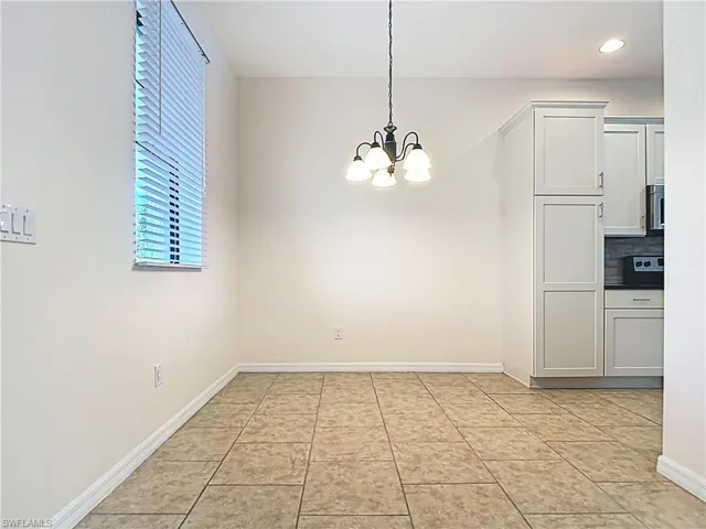 Unfurnished dining area featuring baseboards, a notable chandelier, and recessed lighting