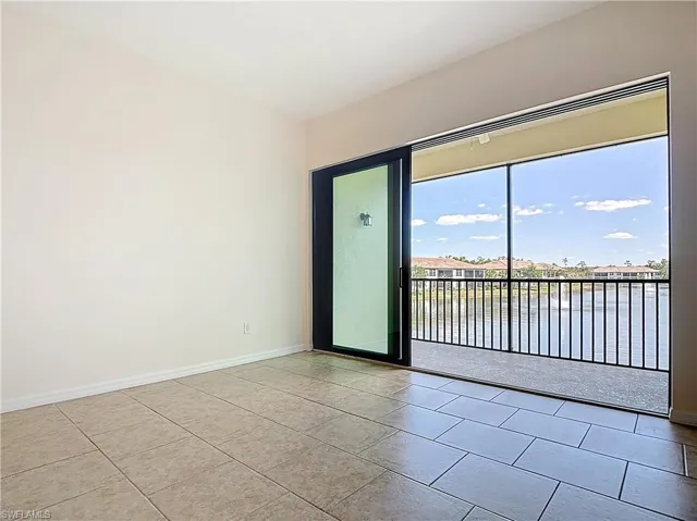 Unfurnished room featuring a water view, tile patterned floors, and baseboards