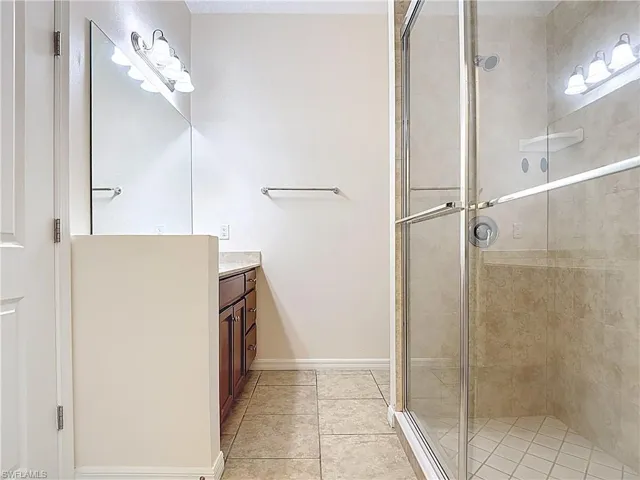 Full bath with baseboards, vanity, and a stall shower