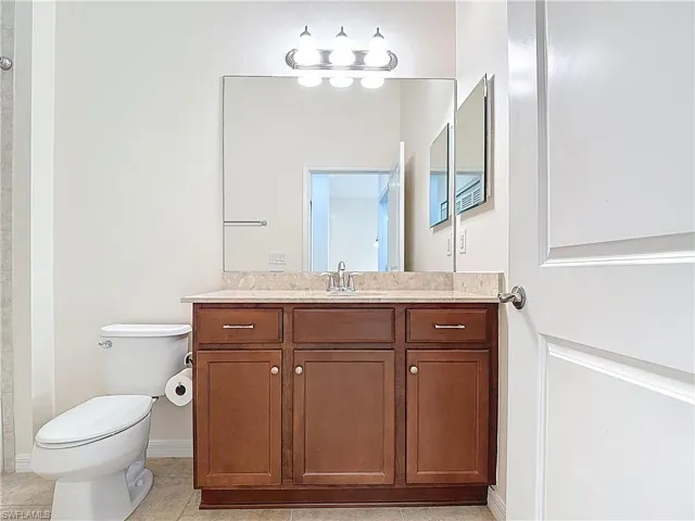 Full bathroom with baseboards, vanity, tile patterned flooring, and toilet