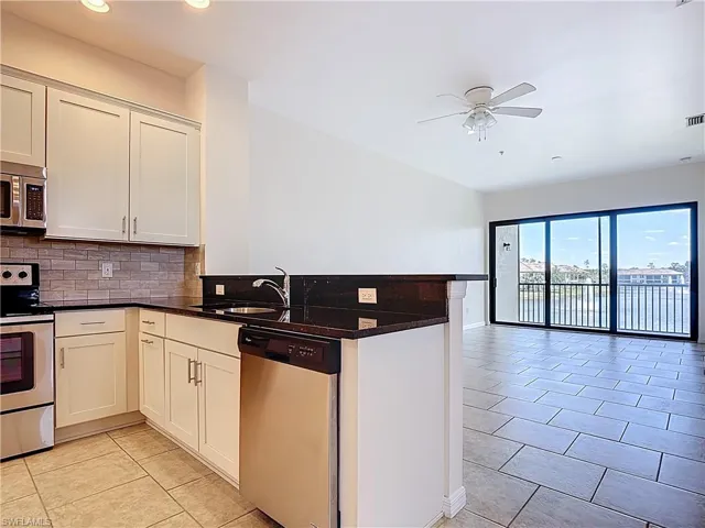 Kitchen with a peninsula, a sink, tasteful backsplash, a ceiling fan, and appliances with stainless steel finishes
