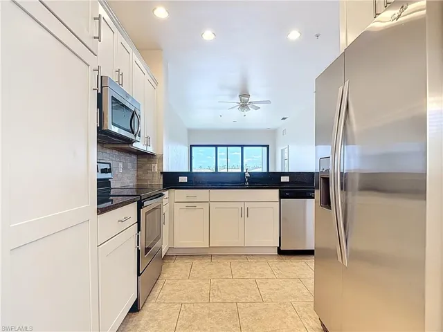 Kitchen featuring stainless steel appliances, dark countertops, recessed lighting, decorative backsplash, and a ceiling fan