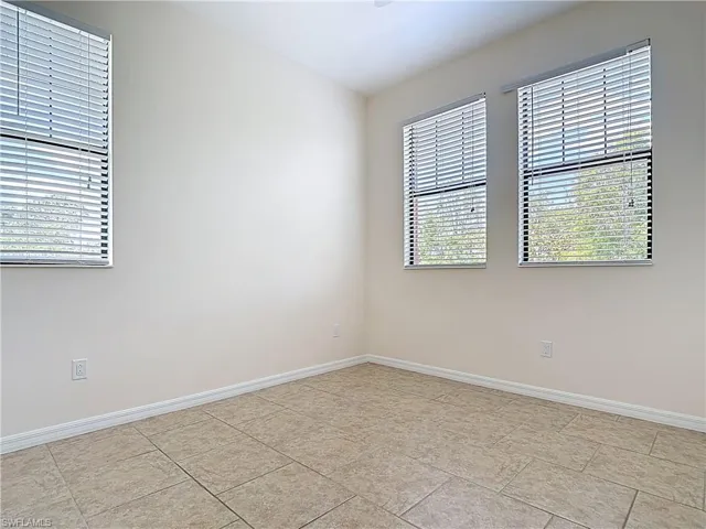 Empty room featuring baseboards and light tile patterned floors