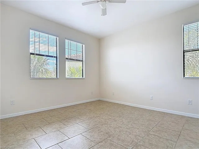 Spare room featuring ceiling fan, baseboards, and plenty of natural light