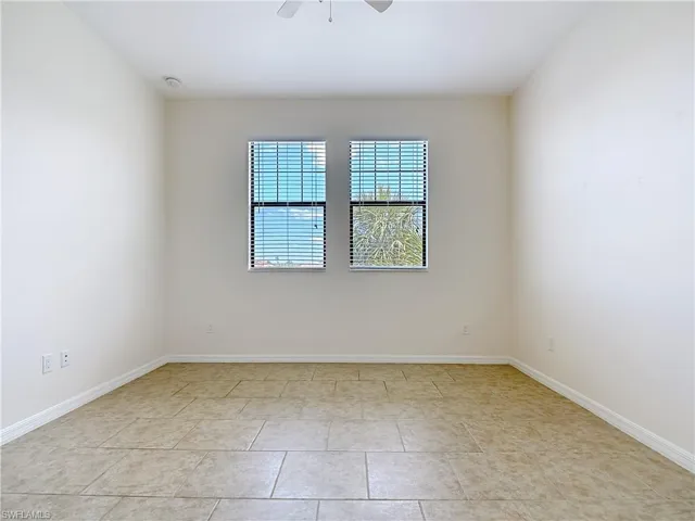 Spare room with ceiling fan, baseboards, and light tile patterned floors