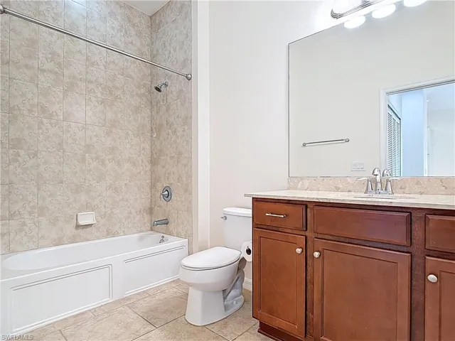 Bathroom featuring shower / bathtub combination, vanity, tile patterned flooring, and toilet