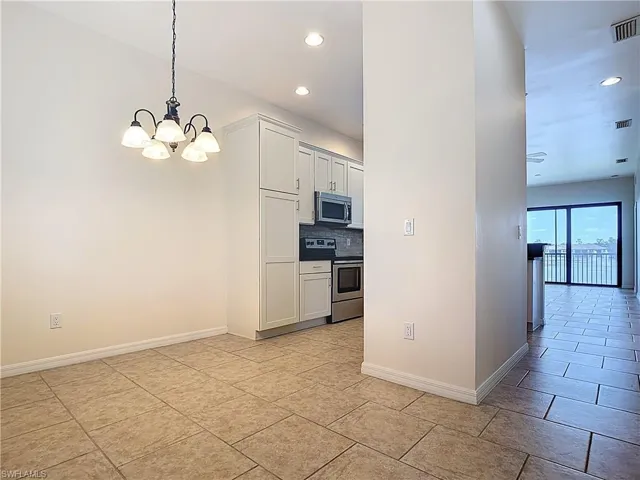 Kitchen with recessed lighting, stainless steel appliances, baseboards, decorative backsplash, and a notable chandelier