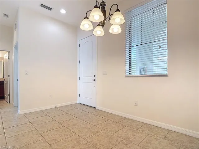 Unfurnished dining area featuring baseboards, visible vents, a chandelier, and light tile patterned flooring