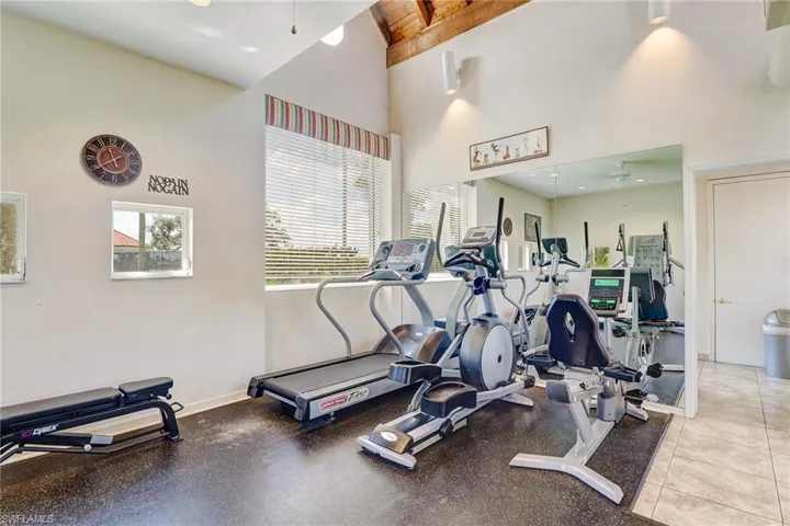 Exercise room with ceiling fan, light tile patterned floors, and a high ceiling