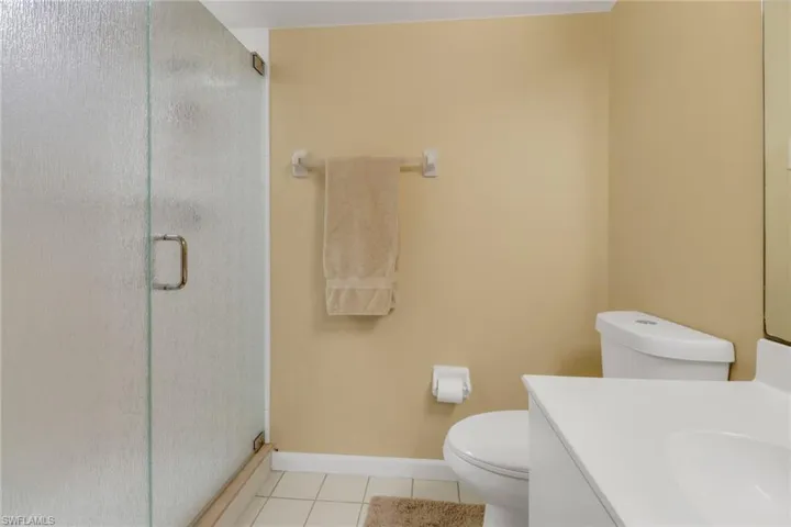 Bathroom with tile patterned flooring, vanity, a shower with door, and toilet