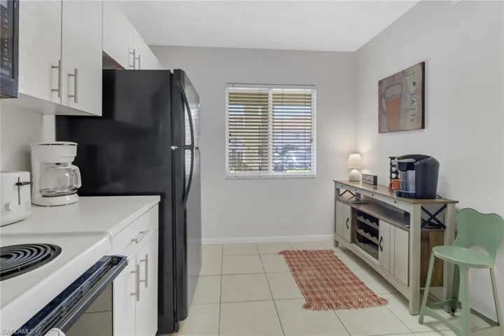 Kitchen with electric range, white cabinetry, and light tile patterned floors