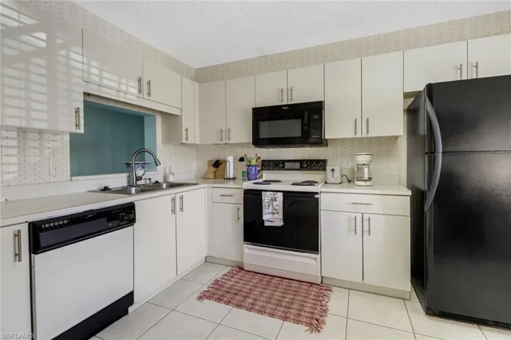 Kitchen featuring black appliances, white cabinetry, and sink