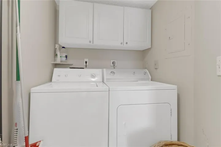 Laundry room featuring washing machine and clothes dryer, electric panel, and cabinets