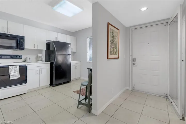 Kitchen featuring white cabinets, light tile patterned flooring, and black appliances