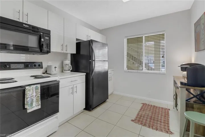 Kitchen featuring black appliances, white cabinetry, and light tile patterned floors