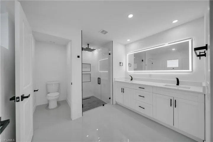 Bathroom featuring a stall shower, double vanity, recessed lighting, and tile patterned floors