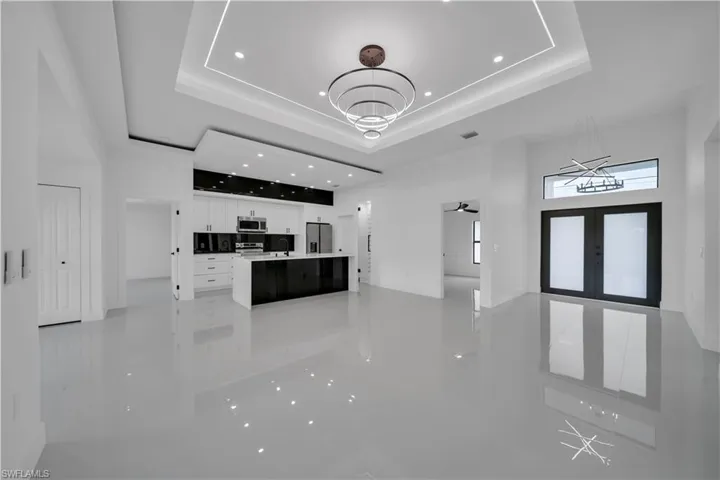 Unfurnished living room with a raised ceiling, a chandelier, recessed lighting, and light tile patterned floors