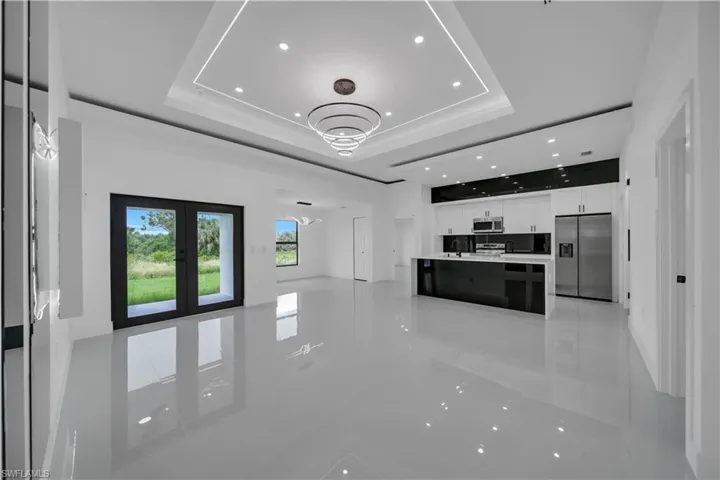 Unfurnished living room featuring a tray ceiling, recessed lighting, french doors, and light tile patterned floors