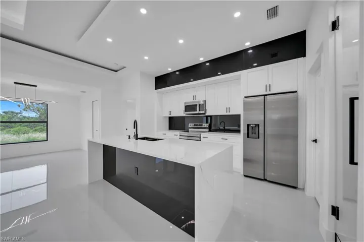 Kitchen with stainless steel appliances, light tile patterned floors, white cabinets, recessed lighting, and light stone counters
