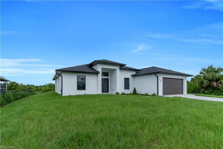 Prairie-style house featuring a garage, driveway, a front lawn, and stucco siding