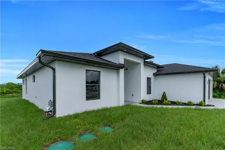 View of side of property featuring stucco siding and a lawn