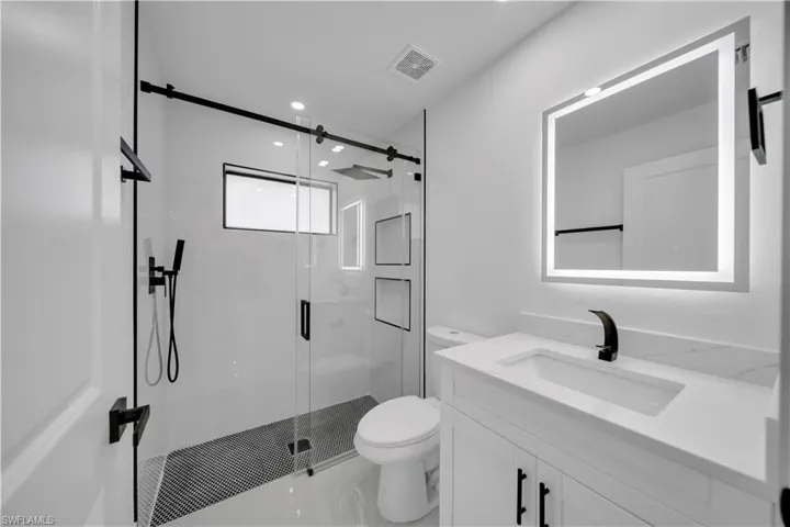 Bathroom with vanity, a shower stall, and recessed lighting