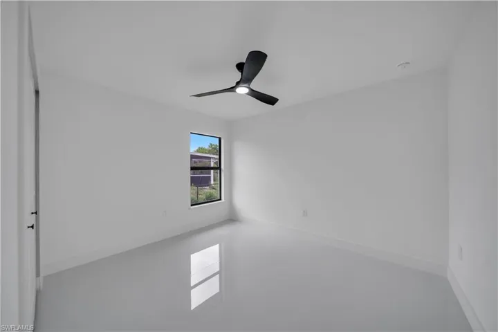 Tiled empty room with ceiling fan and a smoke detector