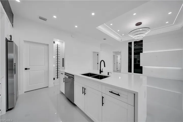 Kitchen featuring stainless steel appliances, white cabinetry, a raised ceiling, light countertops, and recessed lighting