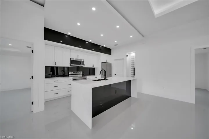 Kitchen with stainless steel appliances, recessed lighting, white cabinetry, a spacious island, and light countertops