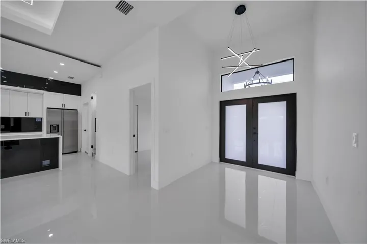 Entryway with a chandelier, french doors, a high ceiling, light tile patterned flooring, and recessed lighting