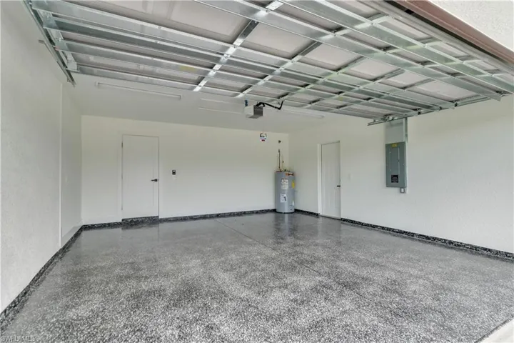 Garage featuring electric panel, water heater, and a garage door opener