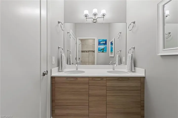 Hall bathroom featuring double sink CUSTOM ITALIAN CABINETRY vanity, solid surface counter, TILE FLOOR and tub/shower with tile surround to the ceiling.
