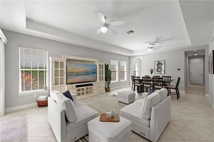 Open great room with TILE FLOOR, floor outlet, TRAY CEILING, and IMPACT GLASS sliding glass doors leading out to the lanai. NEW CEILING FANS (2017), NEW WINDOW BLINDS (2017)