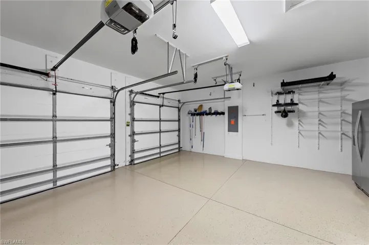 Oversized 2-car garage with garage door opener, NEW GARAGE REFRIGERATOR (2017), NEW EPOXY FLOOR (2017), NEW GAS GRILL (2023), NEW GARAGE STORAGE RACKS/SHELVING (2023), NEW WHOLE HOUSE SURGE PROTECTOR (2023), NEW GARAGE DOOR KEYPADS (2025), and NEW GARAGE DOOR SPRINGS & SENSORS (2025)
