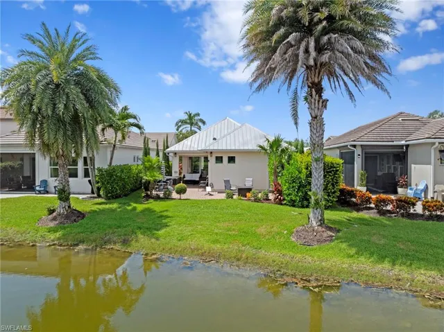 Rear view of the home showing lush landscaping and plenty of room for a future pool/spa with caged lanai. NEW EXTENDED PAVER LANAI (2021), NEW LANDSCAPING (2021), NEW EXTERIOR SECURITY CAMERAS (2025)