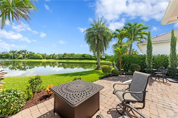 Paver lanai with a water view and view of wooded area. NEW EXTENDED PAVER LANAI (2021), NEW LANDSCAPING (2021), NEW GAS GRILL (2023)
