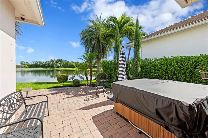Paver lanai featuring a hot tub and a water view. NEW HOT TUB (2020), NEW EXTENDED PAVER LANAI (2021), NEW LANDSCAPING (2021), NEW GAS GRILL (2023), NEW EXTERIOR SECURITY CAMERAS (2025)
