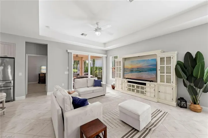 Open great room with TILE FLOOR, floor outlet, TRAY CEILING, and IMPACT GLASS sliding glass doors leading out to the lanai. NEW CEILING FANS (2017), NEW WINDOW BLINDS (2017)