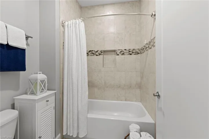 Hall bathroom featuring double sink CUSTOM ITALIAN CABINETRY vanity, solid surface counter, TILE FLOOR and tub/shower with tile surround to the ceiling.
