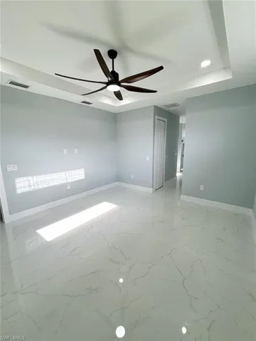 Empty room with ceiling fan and light tile patterned flooring