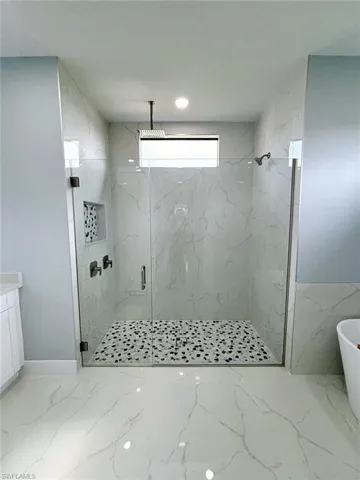 Bathroom with tile walls, vanity, tile patterned flooring, and an enclosed shower