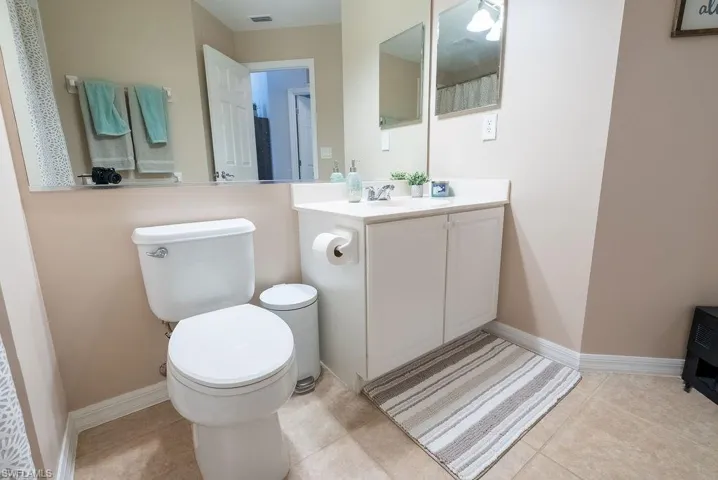 Full bathroom with vanity, light tile patterned flooring, and curtained shower